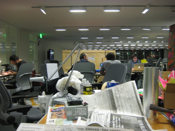 people work in an office area surrounded by chairs and papers