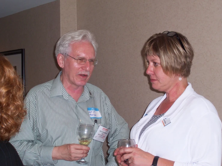 an older man and woman drinking wine at a gathering