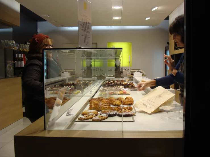 a women who is looking at some pastries behind a counter