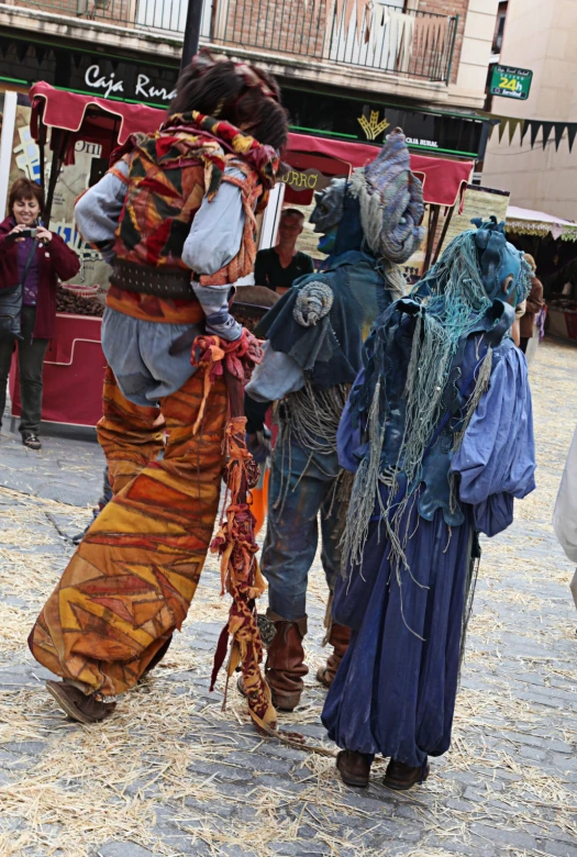 two people dressed in scarecrow costumes are walking on the street