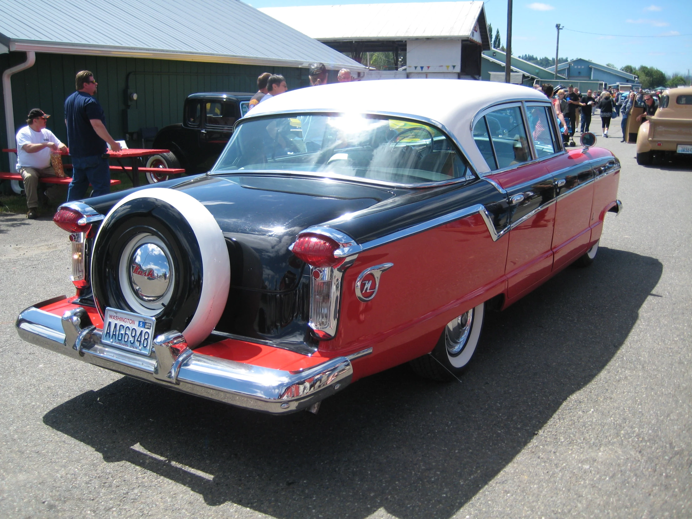 an old red and white car sitting on the street