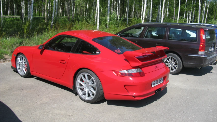 the side of two cars on the street, one is red