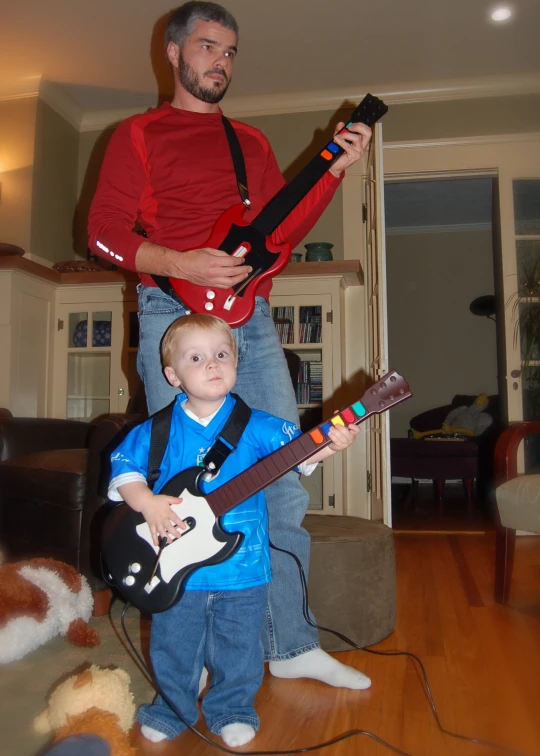 there is a man playing an electric guitar for a boy