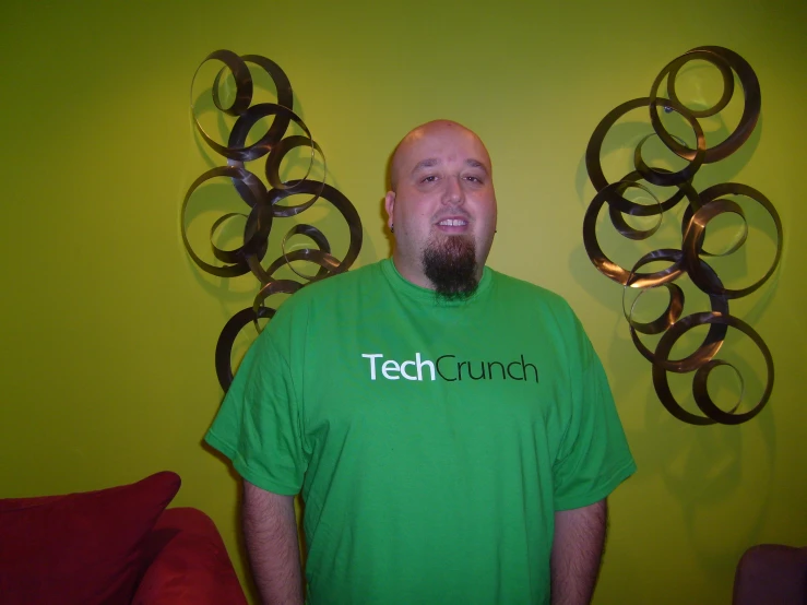 man wearing tech church shirt in front of wall sculptures