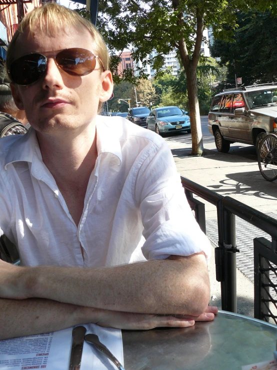 a man sitting in front of a table wearing sunglasses