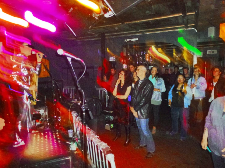 a man in black jacket speaking into microphone at a party