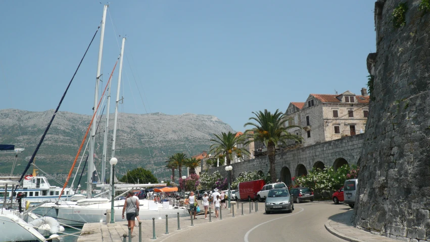 people are gathered around the waterfront watching the boats pass by