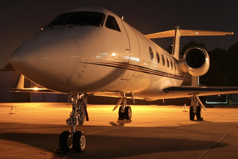 a small jet is sitting on the tarmac at night