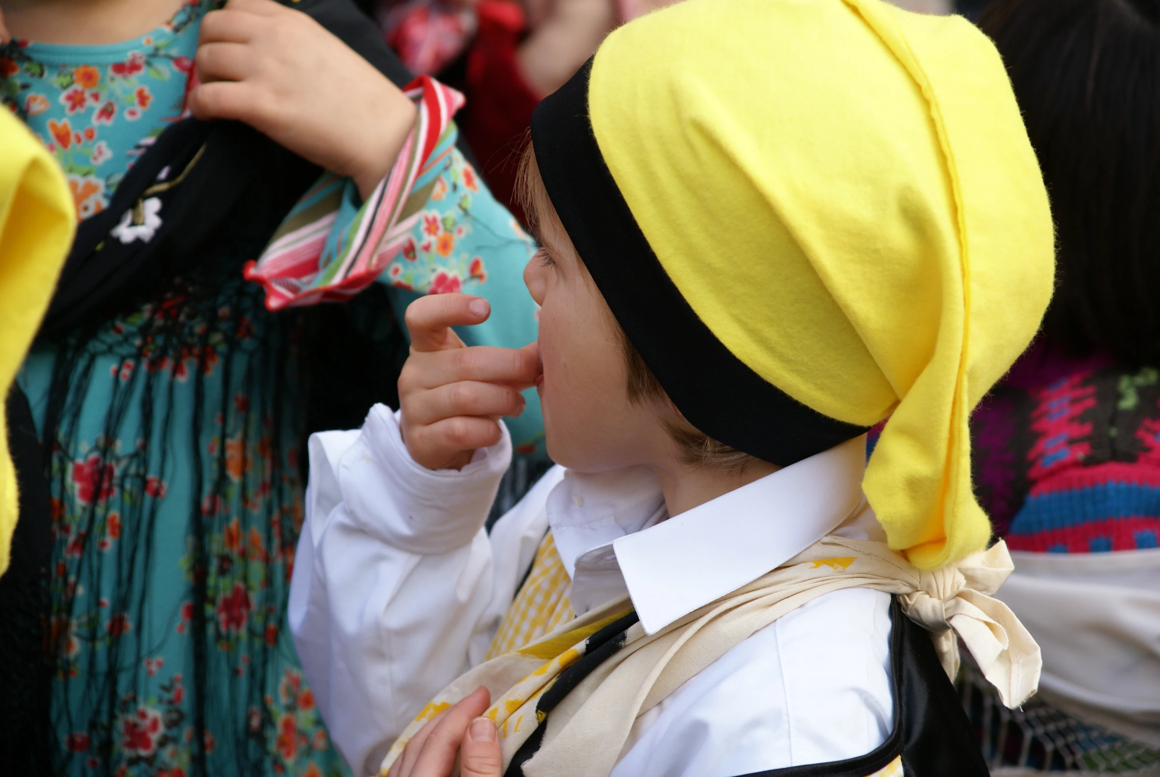 a child dressed in folk clothing wearing a yellow headscarf