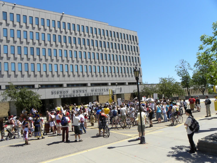 several people stand outside of a large building