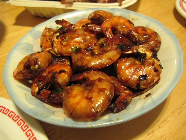 a blue plate with cooked shrimp sitting on top of a table