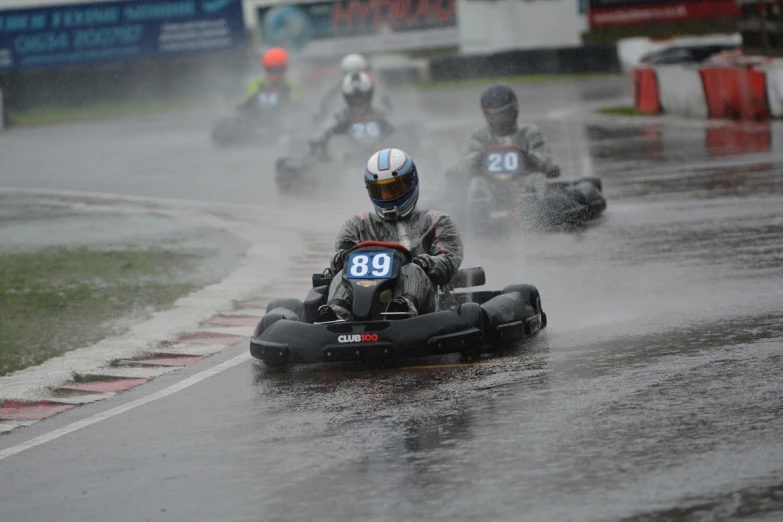 people in go kart racing in the rain