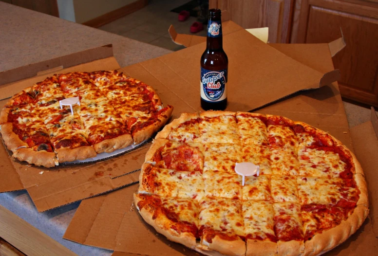 two pizzas sit in boxes, one with pepperoni and cheese