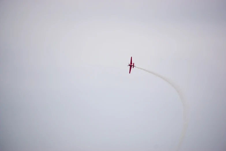 an airplane flying in the air with smoke coming out from its tail