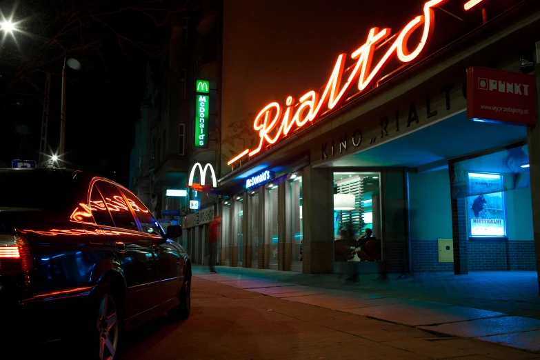 a neon sign on a building above a fast food restaurant