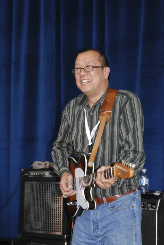 a man holding two electric guitar guitars in front of a microphone