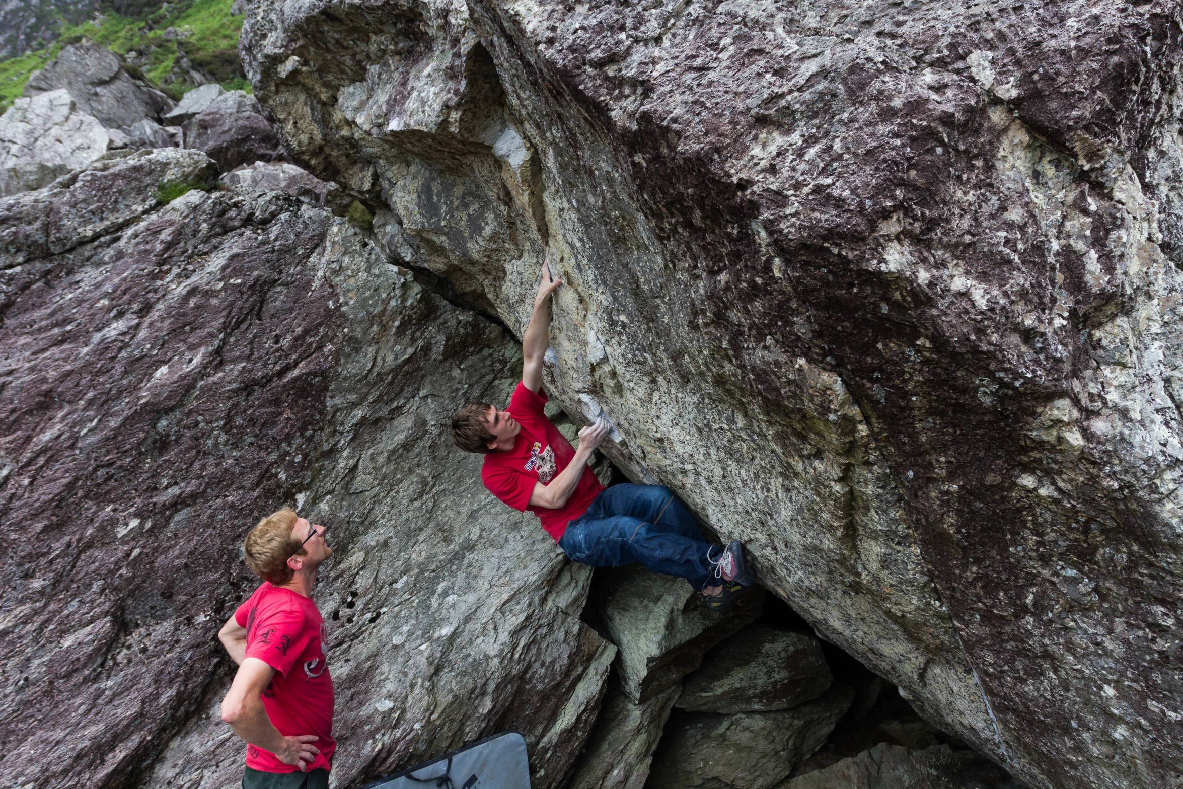 two men climb on the side of a mountain