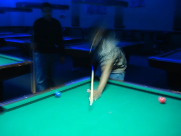 a woman holding a pool bat while leaning over a pool table