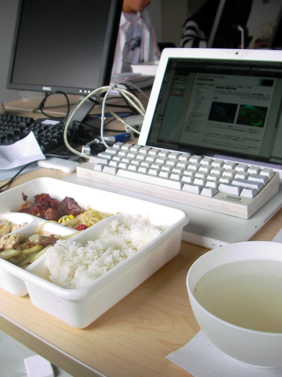 a bowl of food on a desk in front of a laptop