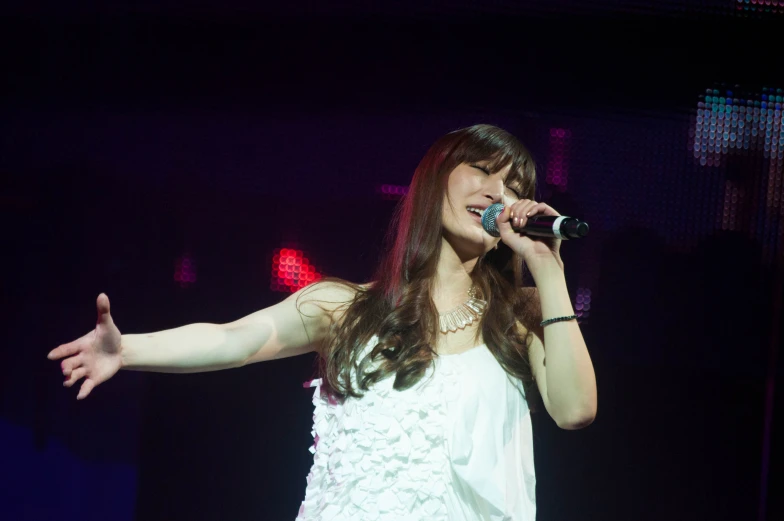 a woman in white singing into a microphone