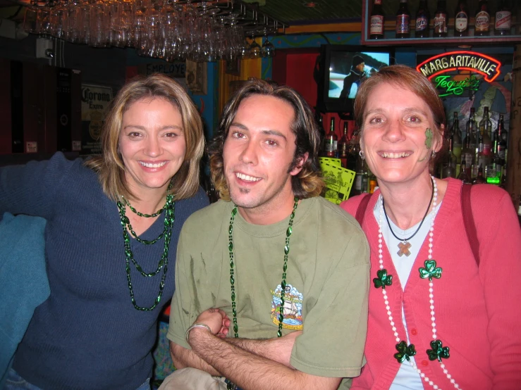 three people sitting together at a bar with beads