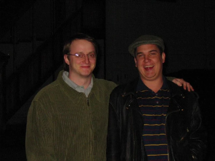 two men posing for the camera in front of stairs