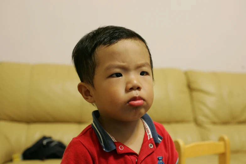 the boy is wearing a red shirt while making a goofy face