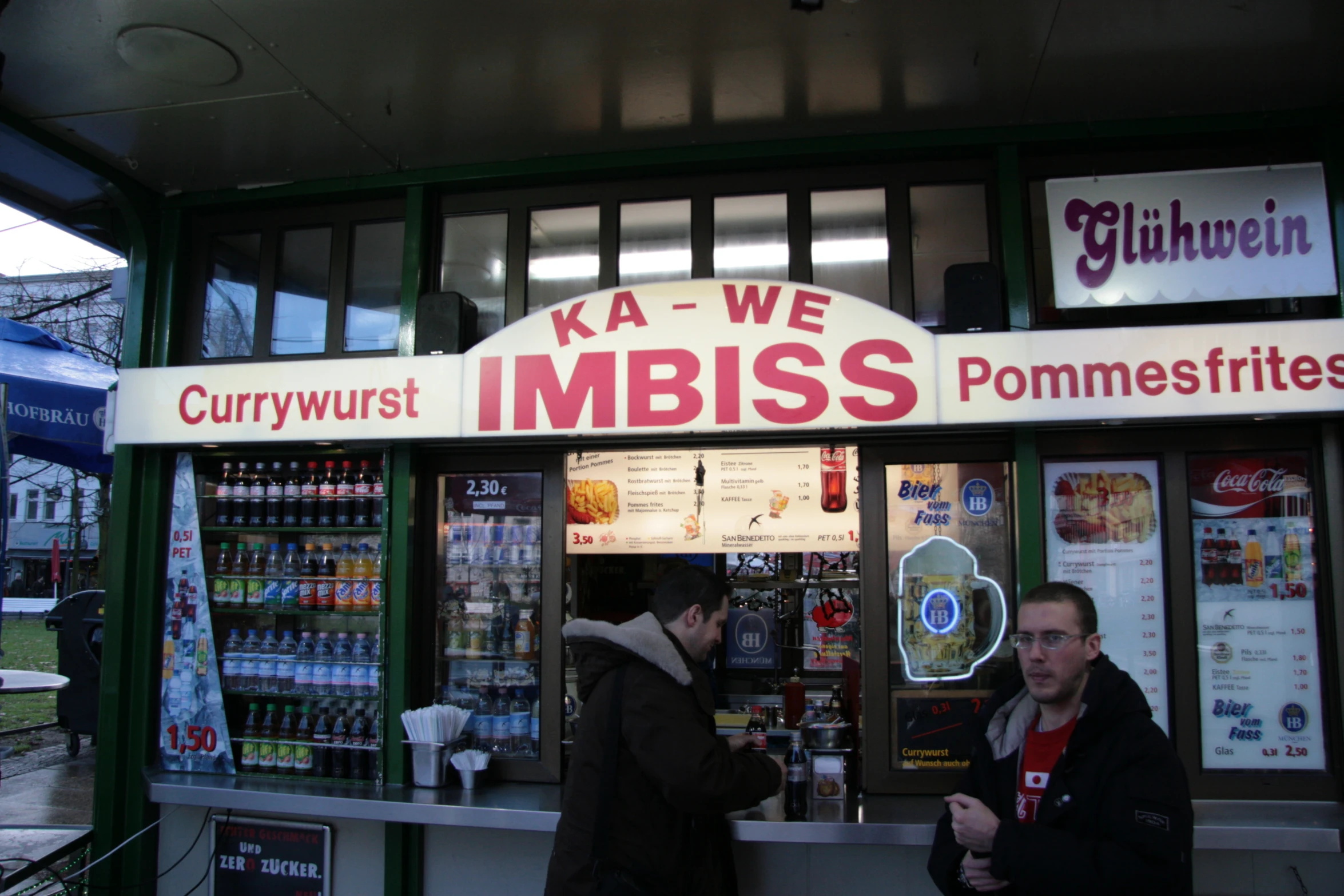 two men are waiting outside of a kiosk