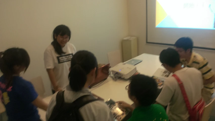 a group of children and adults looking at a projector screen