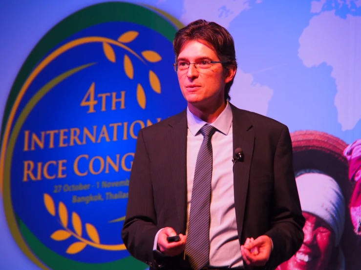 a man in a suit is standing in front of the international rice congress logo