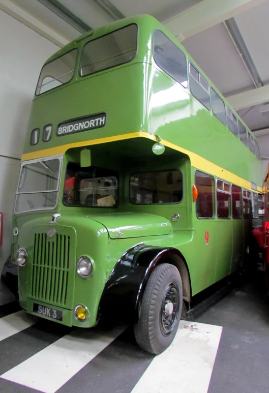 an old, green double - decker bus parked inside a garage