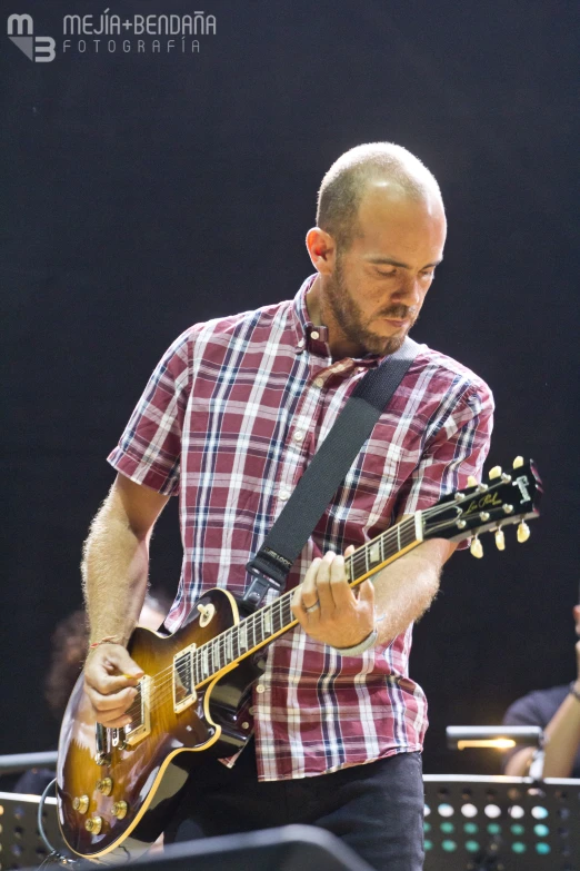 a man playing guitar while a band performs behind him
