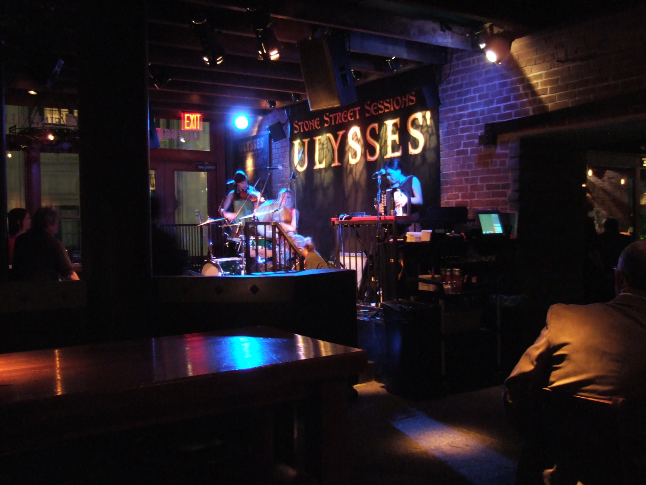 a band on stage in the dark with people sitting at tables