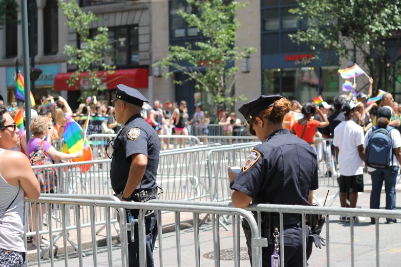 two police officers stand at the fence on a city street