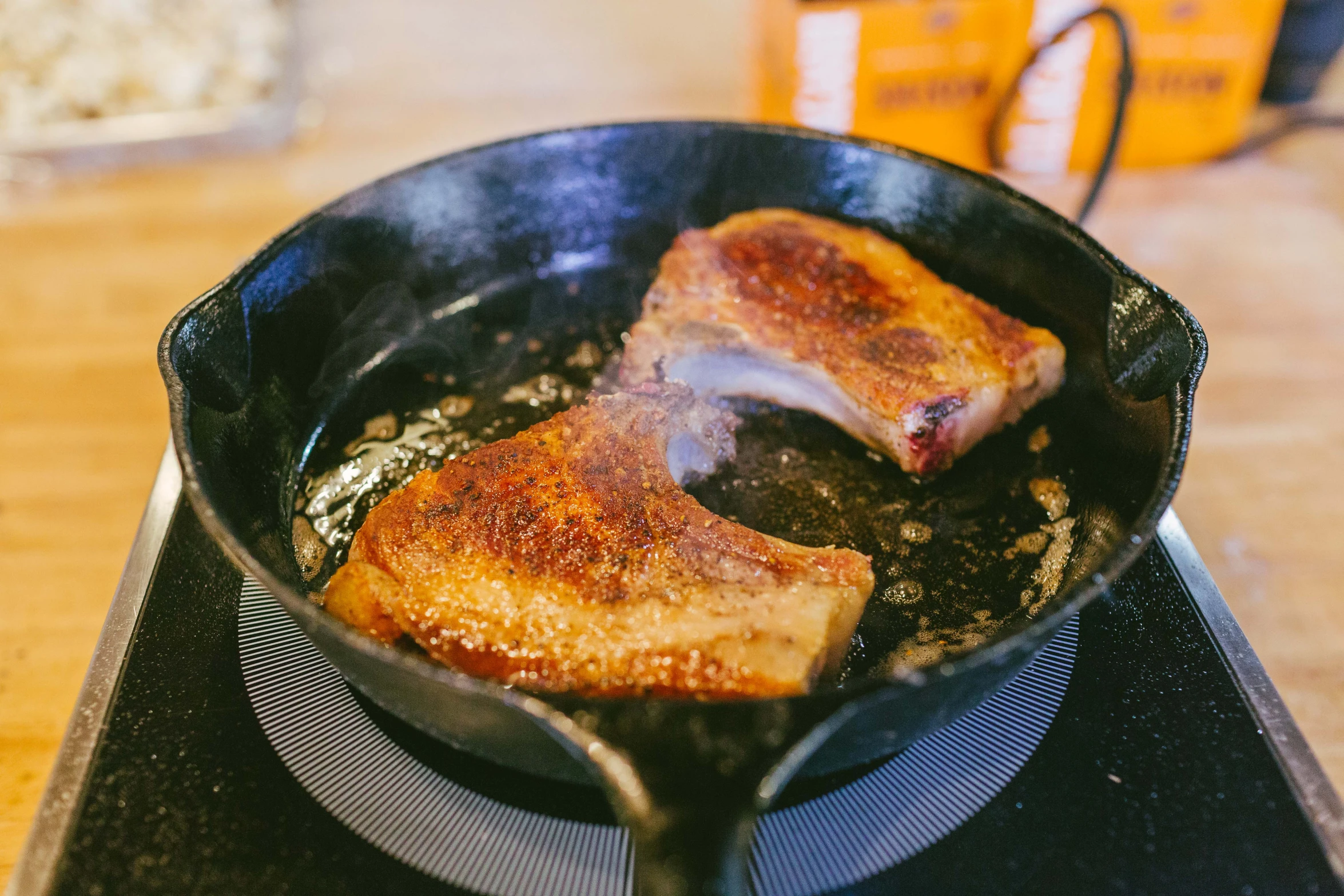 a cast iron set with pork chops cooking in oil