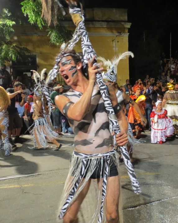 man with feathers performing in front of many spectators