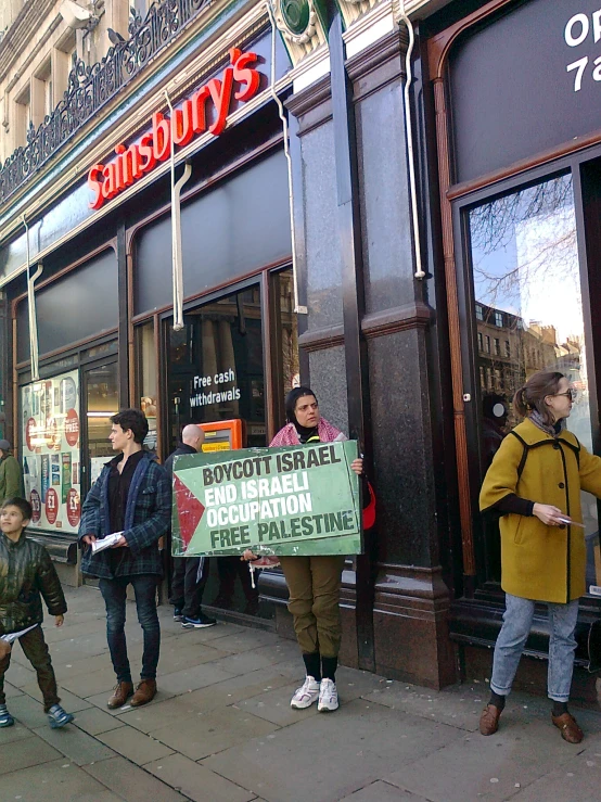 a group of people standing outside a store in front of a tall building