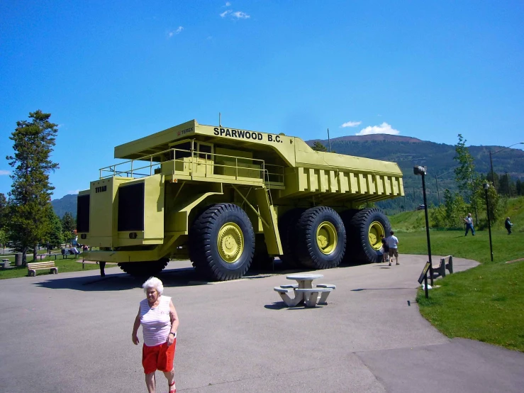 a person walking in front of a giant yellow dump truck