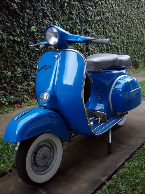 an old fashioned blue scooter on the sidewalk