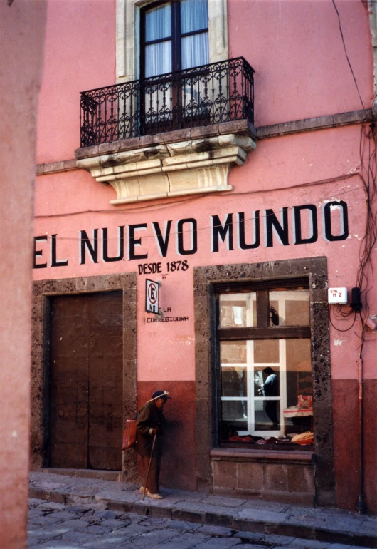 a pink building with a woman sitting on the step