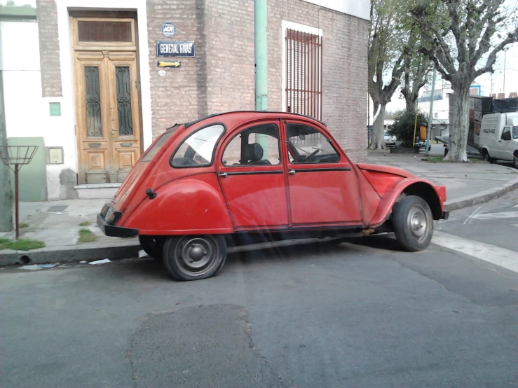 an old - fashioned red car sits parked near the curb