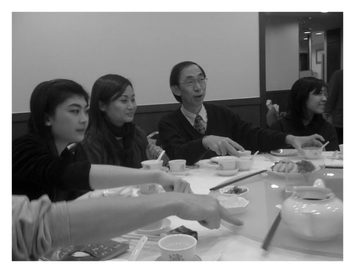 group of people eating chinese food in a long table