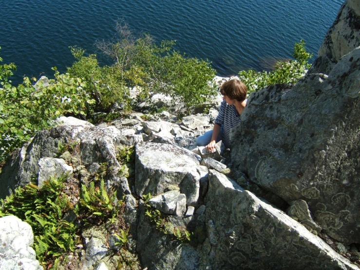 a woman is sitting on the edge of some rocks