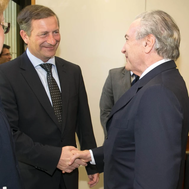 two men shaking hands, while wearing suits