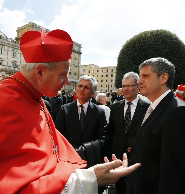 a man in a suit and tie is talking to other men