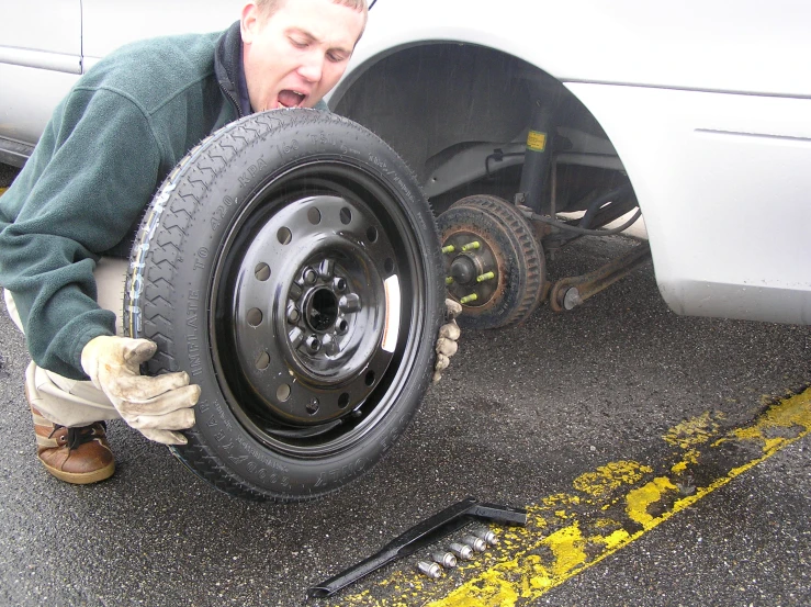 a man adjusts a tire on the ground with his hand