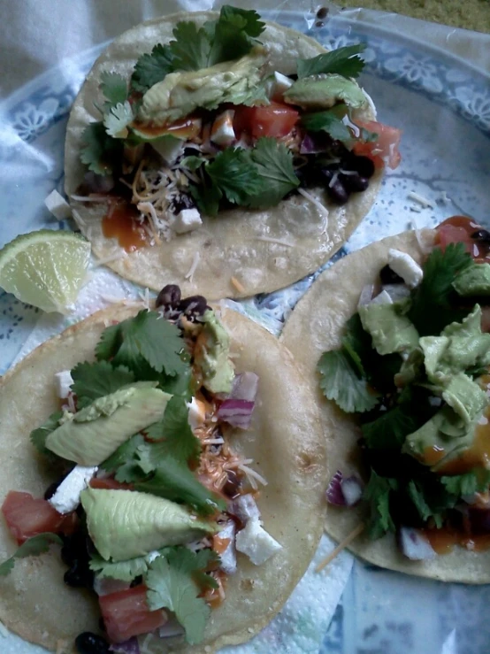 three tacos filled with veggies and avocado on a platter