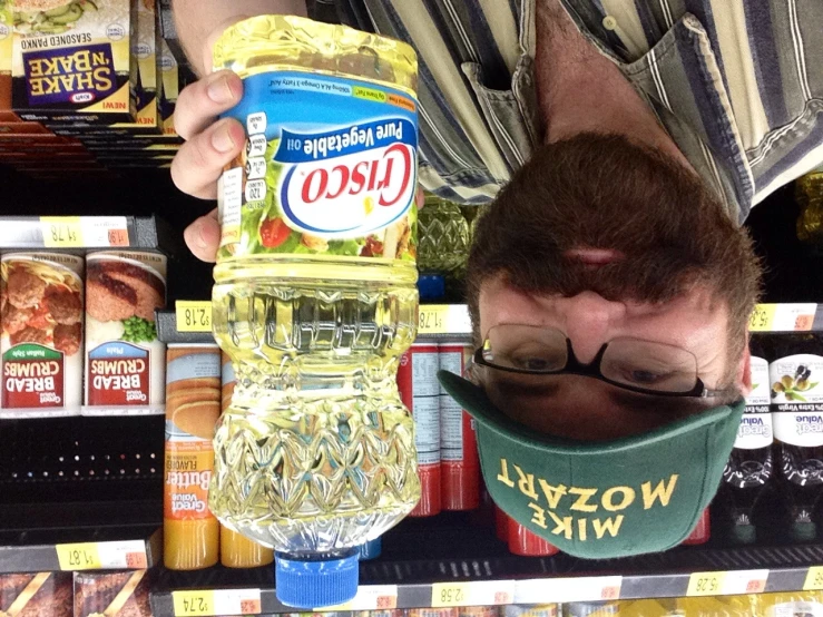 a man wearing glasses holding up a plastic bottle of food