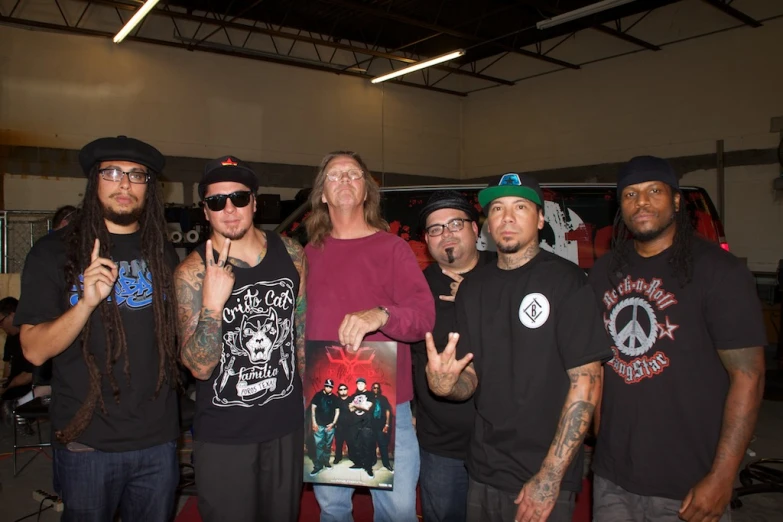 four guys and one woman are wearing black shirts and one is with a peace sign