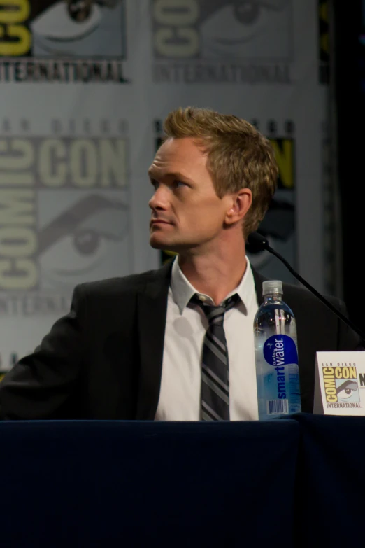 a man in a suit at a convention sitting on a stage